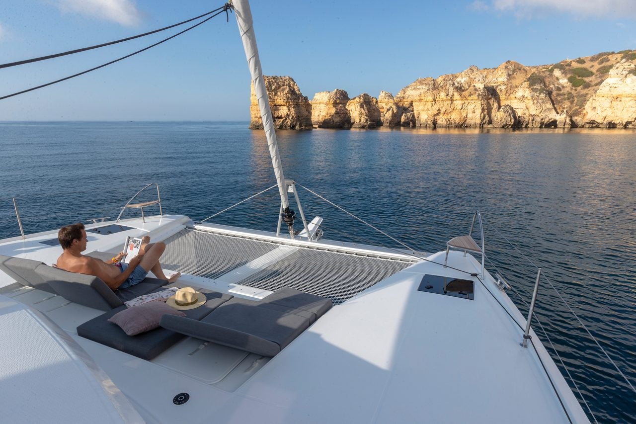 Man on foredeck lounger on Elba 45 catamaran sailboat