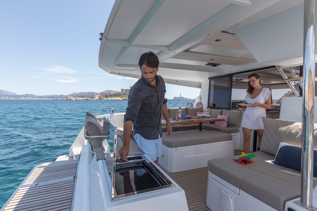 Couple grilling on Fountaine Pajot Astrea 42 catamaran sailboat