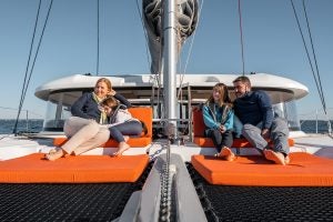 Family sitting on foredeck trampolin of Excess 14 catamaran sailboat