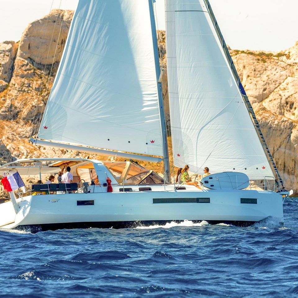 Jeanneau Sunloft 47 sailing near rugged cliffs