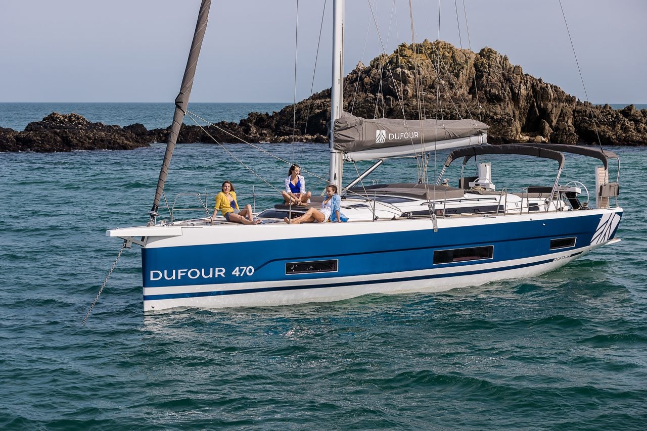 Dufour 470 electric sailboat at anchor with people on bow