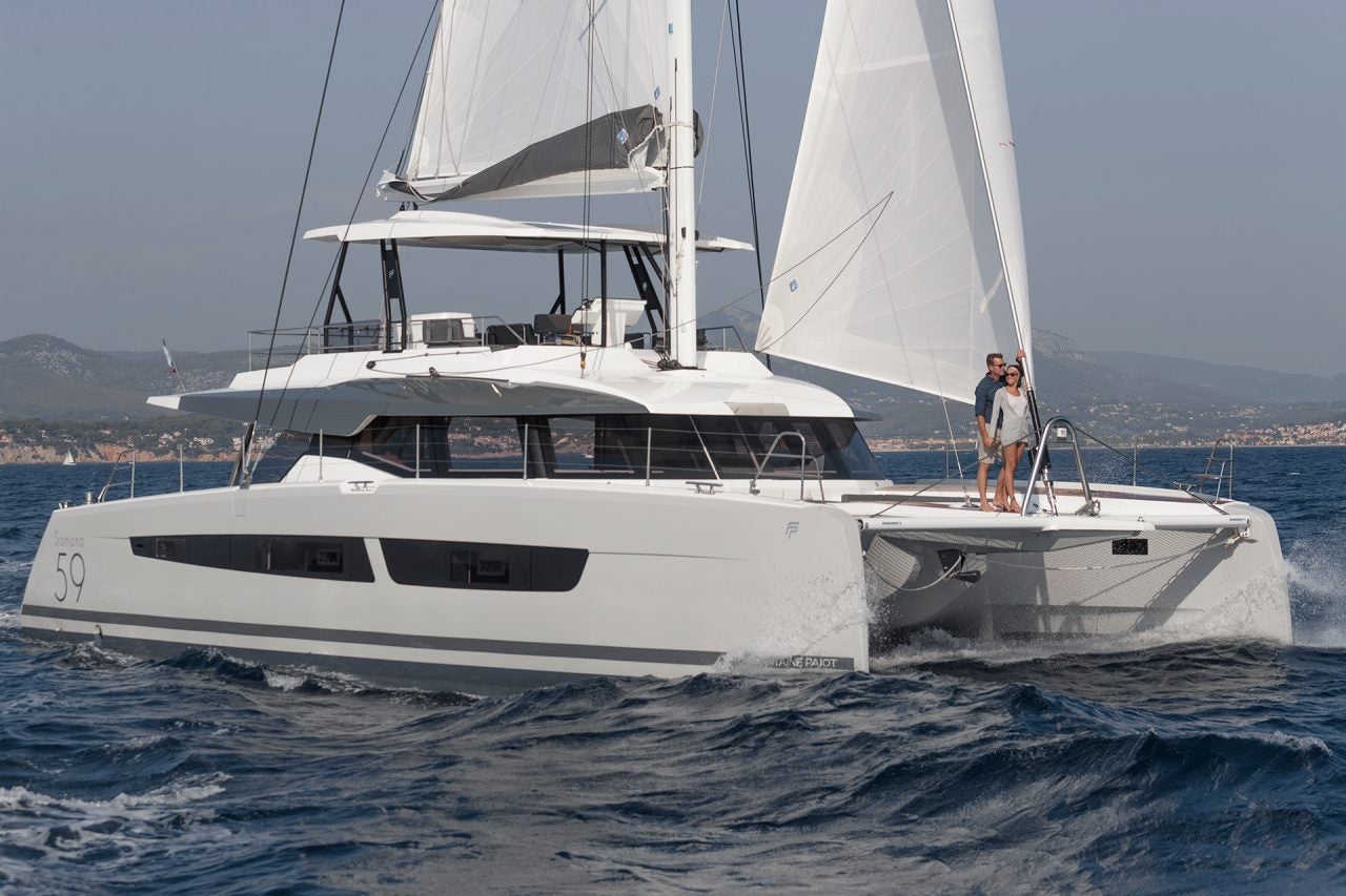 Couple on front of the Samana 59 catamaran while under sail