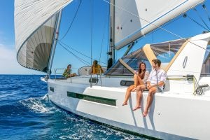 Couple seated on side deck of the Sun Loft 47 sailboat