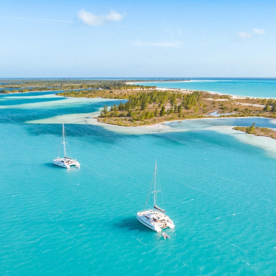 View of line of islands with three Dream Yacht catamarans in blue waters