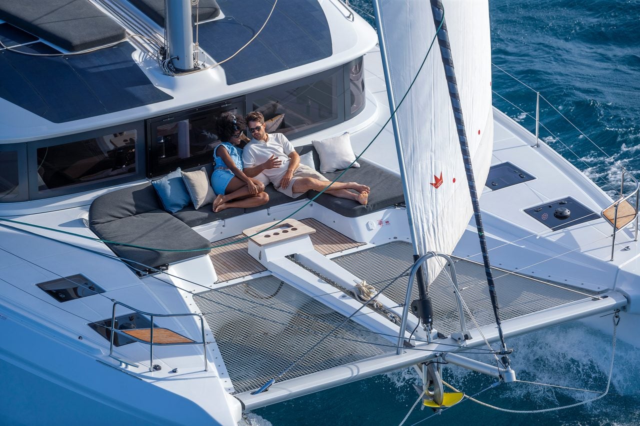 Couple on front deck of new catamaran sailboat yacht model for sale