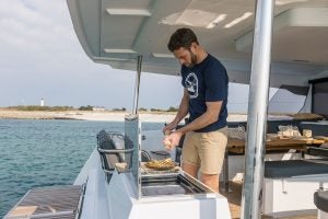 Man using the outdoor grill on the Fountaine Pajot Aura 51 electric catamaran