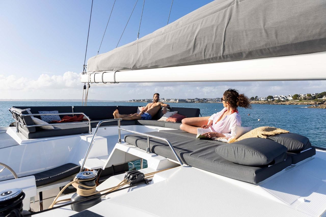 Couple on flybridge lounge area of the Fountaine Pajot Aura 51 electric catamaran