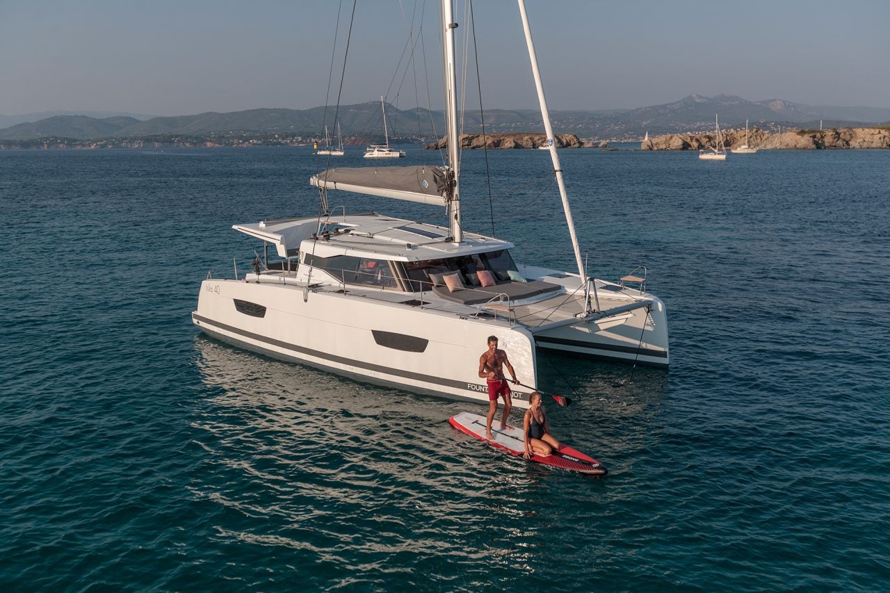 Man paddleboarding next to Isla 40 sailing catamaran