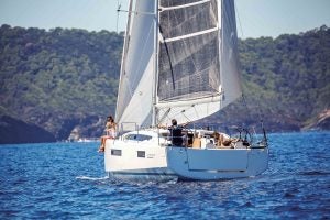 Sun Odyssey 410 monohull sailing with green mountain backdrop