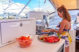 Woman cooking on outdoor galley grill on the Jeanneau Sun Loft 47 monohull